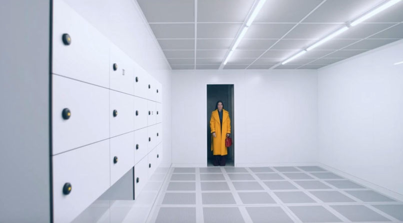 a photo of demi moore standing in a yellow coat in the substance, used in a review of the substance movie