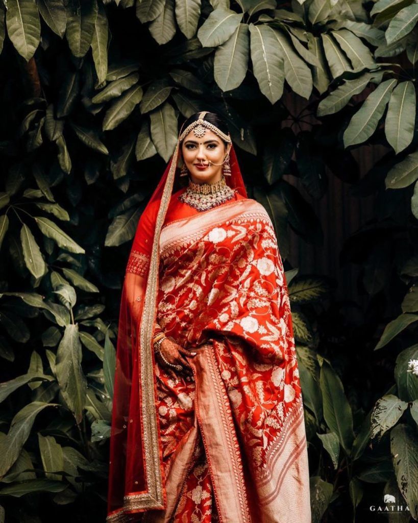 An Indian bride wearing red saree, braided hair and gold jewelry, looking  at camera Stock Photo - Alamy