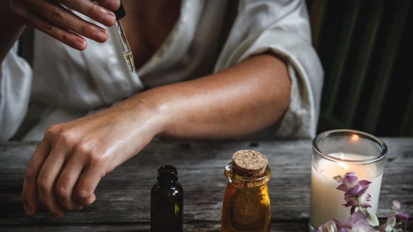 Woman applying jojoba oil on arms